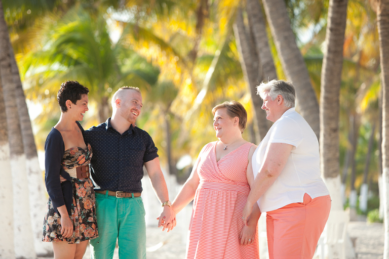 Same sex family holding hands on beach in Mexico