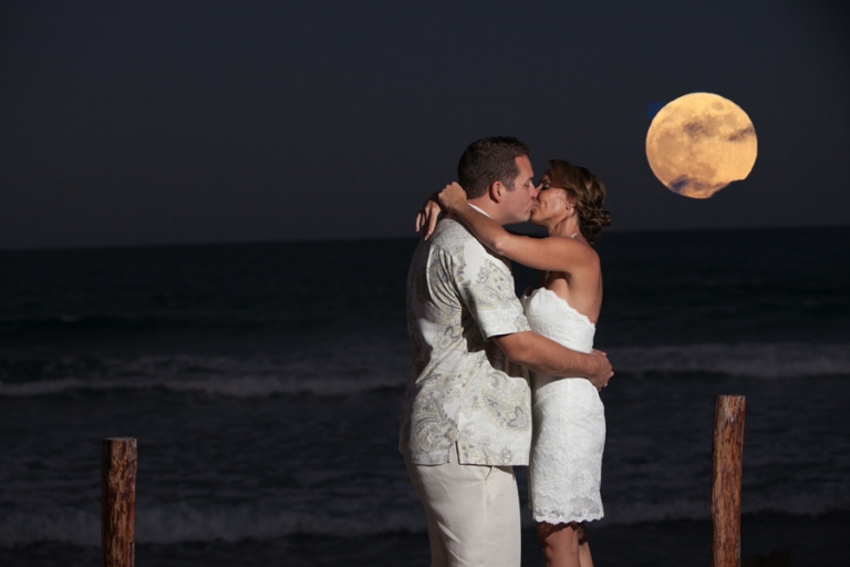 Bride and groom kissing with full moon