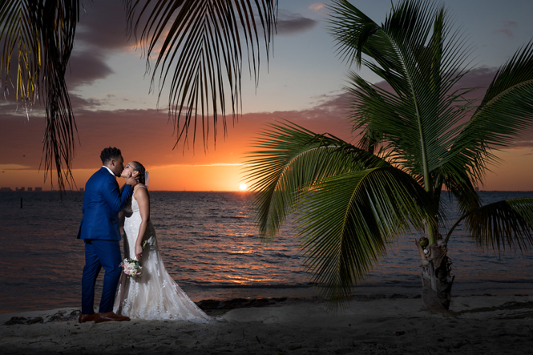 Bride and groom kissing at sunset on beach